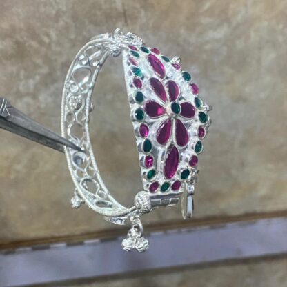 This beautiful bangle features amethyst and peridot gemstones set in a polished silver band. It's a perfect accessory for any occasion.