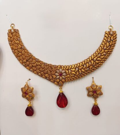 A stunning 21K gold Madrasi choker necklace set featuring an elegant floral design and deep ruby-red teardrop pendants. Comes with matching earrings for a complete traditional look.