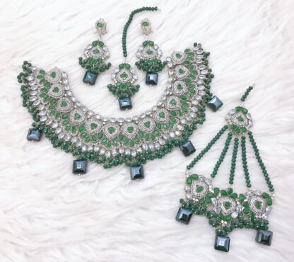 Exquisite silver and deep green Kundan choker set, featuring shimmering stones, intricate beadwork, and complementing jewelry pieces.