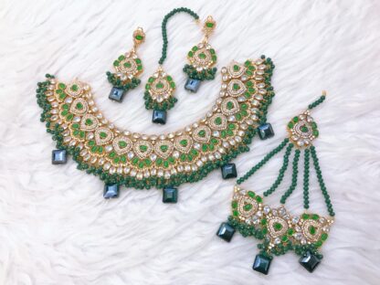 Traditional Kundan choker set in gold and emerald green, featuring delicate bead strands, statement stonework, and matching jewelry pieces.