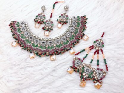 Traditional gold and ruby red Kundan choker set with intricate detailing, bead embellishments, and matching earrings, tikka, and hand jewelry.