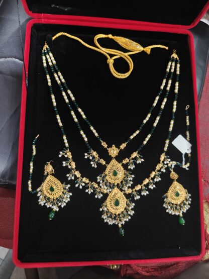 Luxury 2 Tola 21K gold bridal set with layered green and pearl beads, filigree pendant, and matching drop earrings displayed in velvet box.