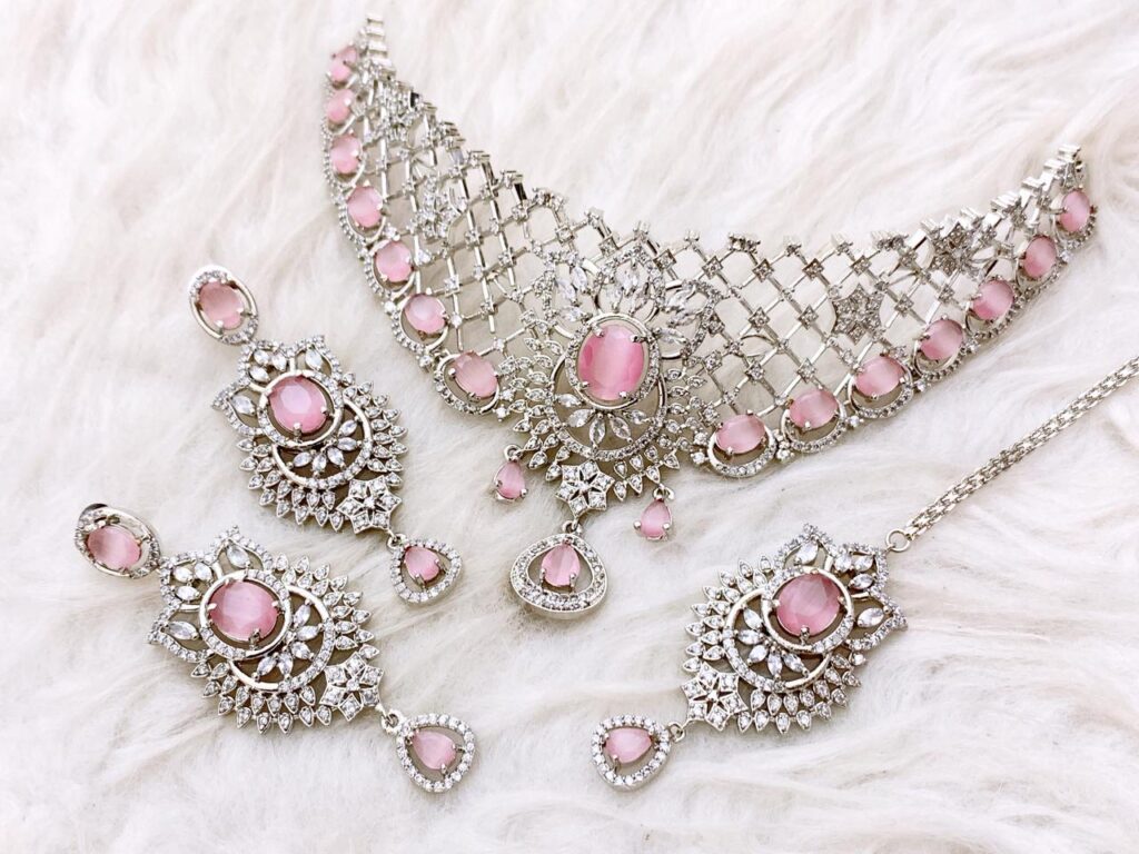 Elegant Silver AD Zircon Choker Necklace Set with bright Ruby Pink oval stones. Includes delicate filigree earrings and Maang Tikka. Perfect for Engagement or formal party wear.