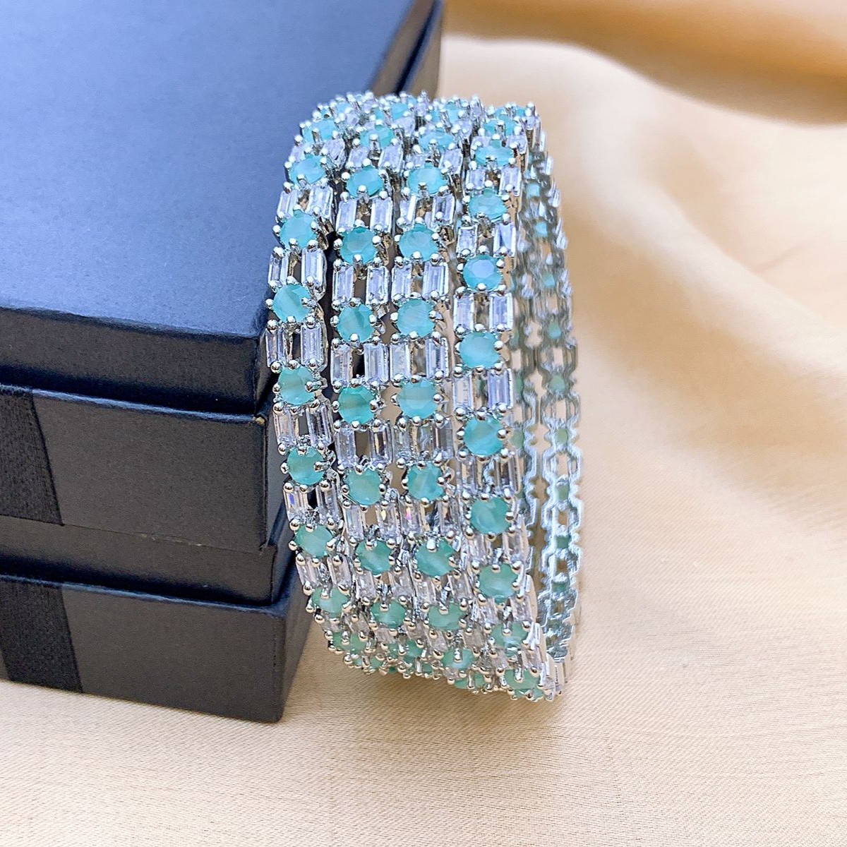 Mint Green AD Bangles (Set of 4) Elegant silver bangles featuring mint green rectangular stones and clear American Diamonds, styled on a dark box for a premium festive look.