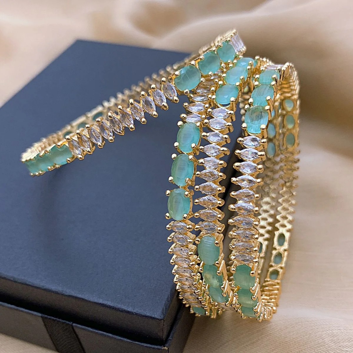 Mint Green AD Bangles (Set of 4) Zoomed-in view of mint green and diamond-like stones set in gold bangles, showcasing intricate craftsmanship and symmetrical design.