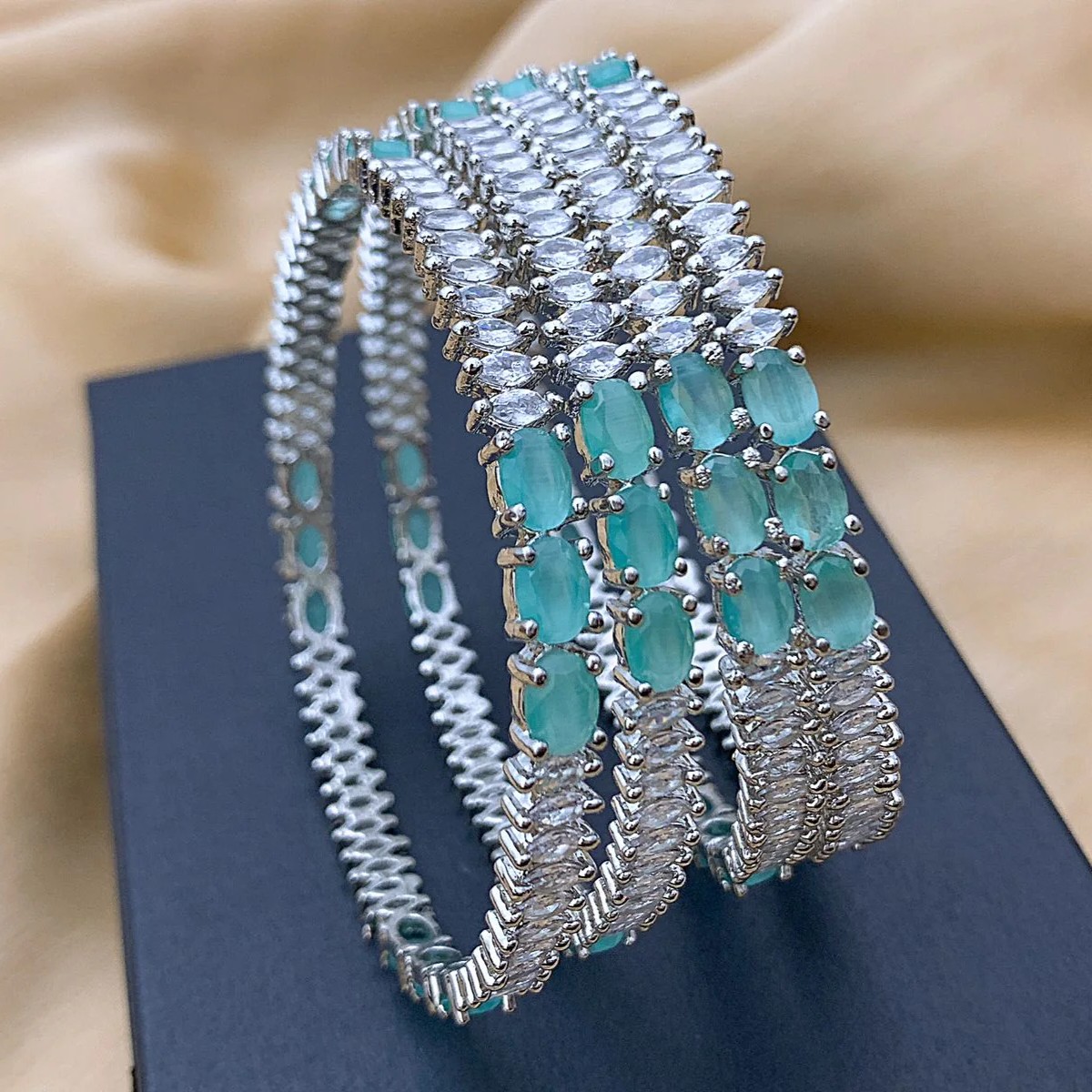 Mint Green AD Bangles (Set of 4) Styled presentation of silver bangles with mint green stones placed on a ribboned box, ideal for bridal, Eid, or formal wear promotions.