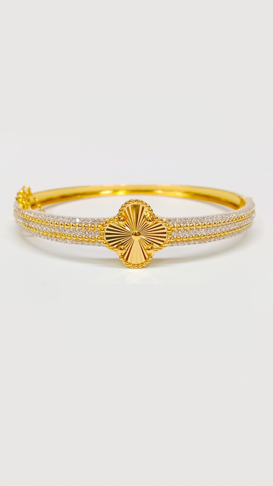 Luxury 22ct Gold Bangle Collection: Clover Designs and Intricate Finishes Luxurious 14.500 Grams gold bangle with a central sunburst clover design and a thick band encrusted with double rows of white stones and gold beads.