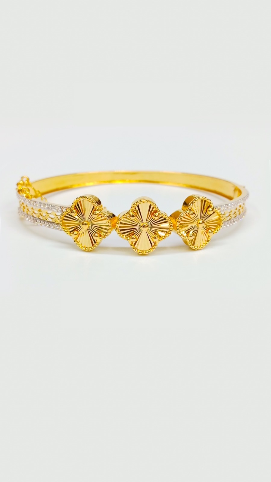 Luxury 22ct Gold Bangle Collection: Clover Designs and Intricate Finishes Stunning 15.300 Grams gold hinged bangle featuring three clover-style medallions and pave diamond-like white stones on the band.
