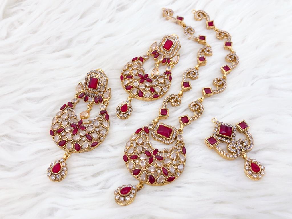 Ruby Red Ornate Gold-Plated Jewelry Set Shop our Traditional Ruby Red & Gold Jewelry Set. Includes Chandbali necklace, large drop earrings, and maang tikka. Perfect for weddings and festive wear.