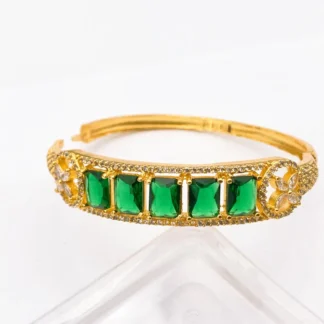 Gold-tone bangle featuring five emerald-cut green crystals with brilliant American Diamond details.