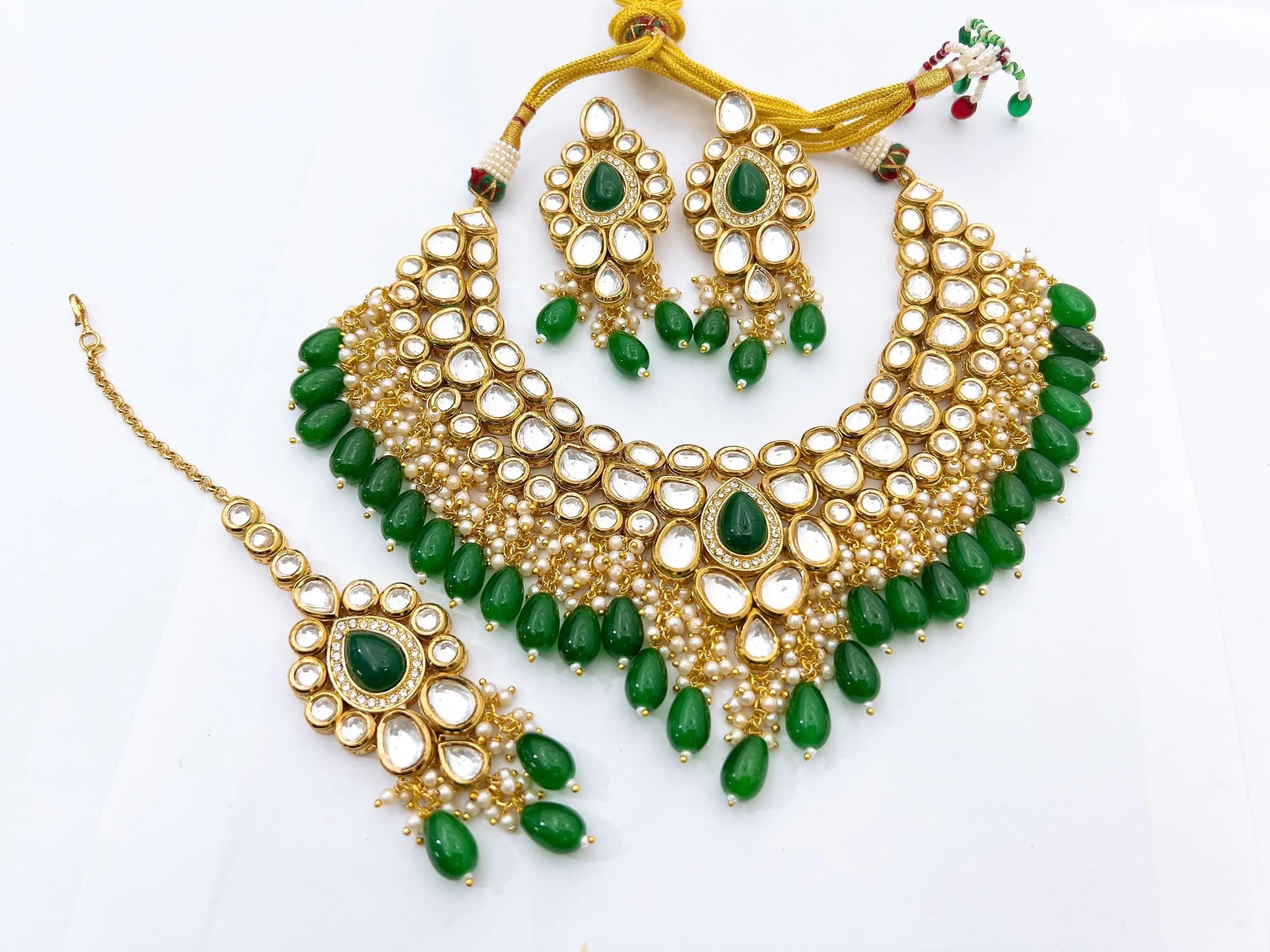 Royal Emerald Green Meenakari Kundan Choker Set with Earrings & Maang Tikka Luxurious Emerald Green Meenakari Kundan bridal choker set with teardrop green beads, matching statement earrings, and maang tikka.