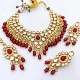 Royal Ruby Red Kundan Bridal Choker Set with Matching Earrings & Maang Tikka Grand ruby red Kundan bridal choker necklace with teardrop red beads, matching earrings, and maang tikka on a white background.