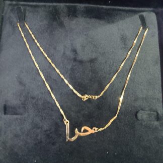 Shop our 22k solid gold personalized Arabic name necklace set. Featuring a custom hand-finished "Hira" (حرا) pendant on a high-shine twisted Singapore wave chain. A perfect heritage gift.