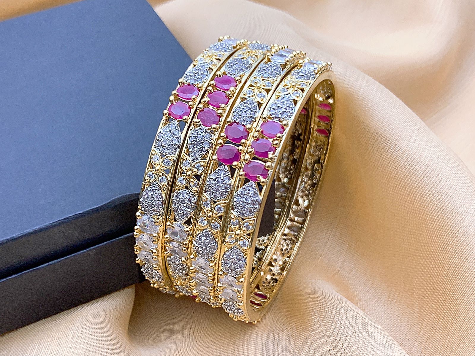 Luxury multi-tone American Diamond bridal bangles set for women in UAE featuring gold and silver finish with pink and white sparkling stones for wedding and formal occasions. Elegant multi-tone American Diamond bridal bangles set featuring gold and silver accents with pink and white AD stones. Designed for weddings and luxury events in the UAE, offering refined sparkle and sophisticated style.