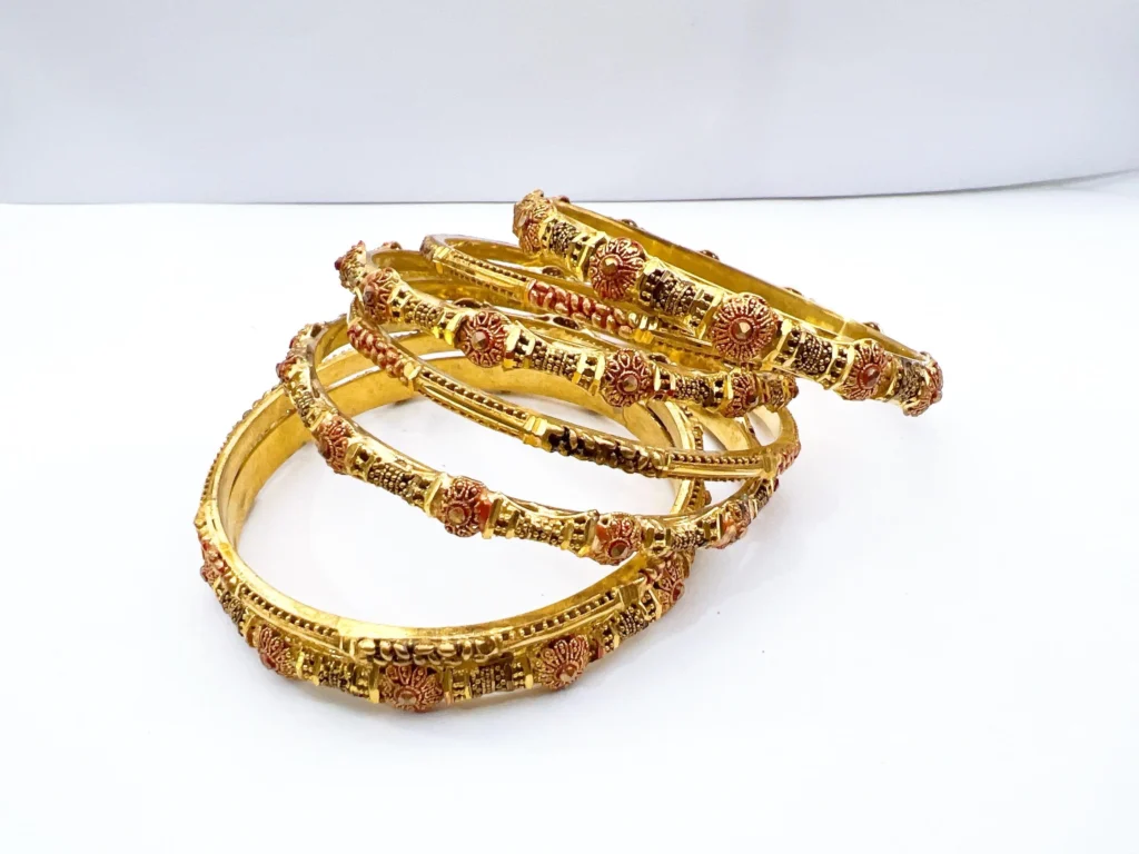 Set of seven premium 22ct gold-plated 1-gram bridal chooriyan bangles featuring raised antique sunburst wheel medallions, textured intervals with deep red enamel, and dual micro-beaded borders.