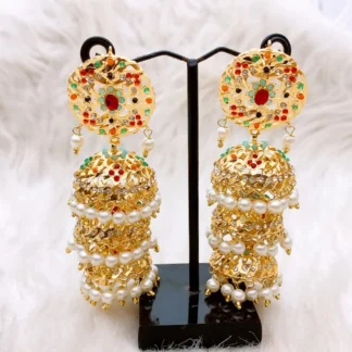 Elaborate multi-tiered jhumka earrings featuring a circular stud with a central red stone and multicolored stone accents, hanging kundan drops, and a dramatic three-step stacked jhumka dome design accented with sparkling white stones and delicate dangling kundan beads.
