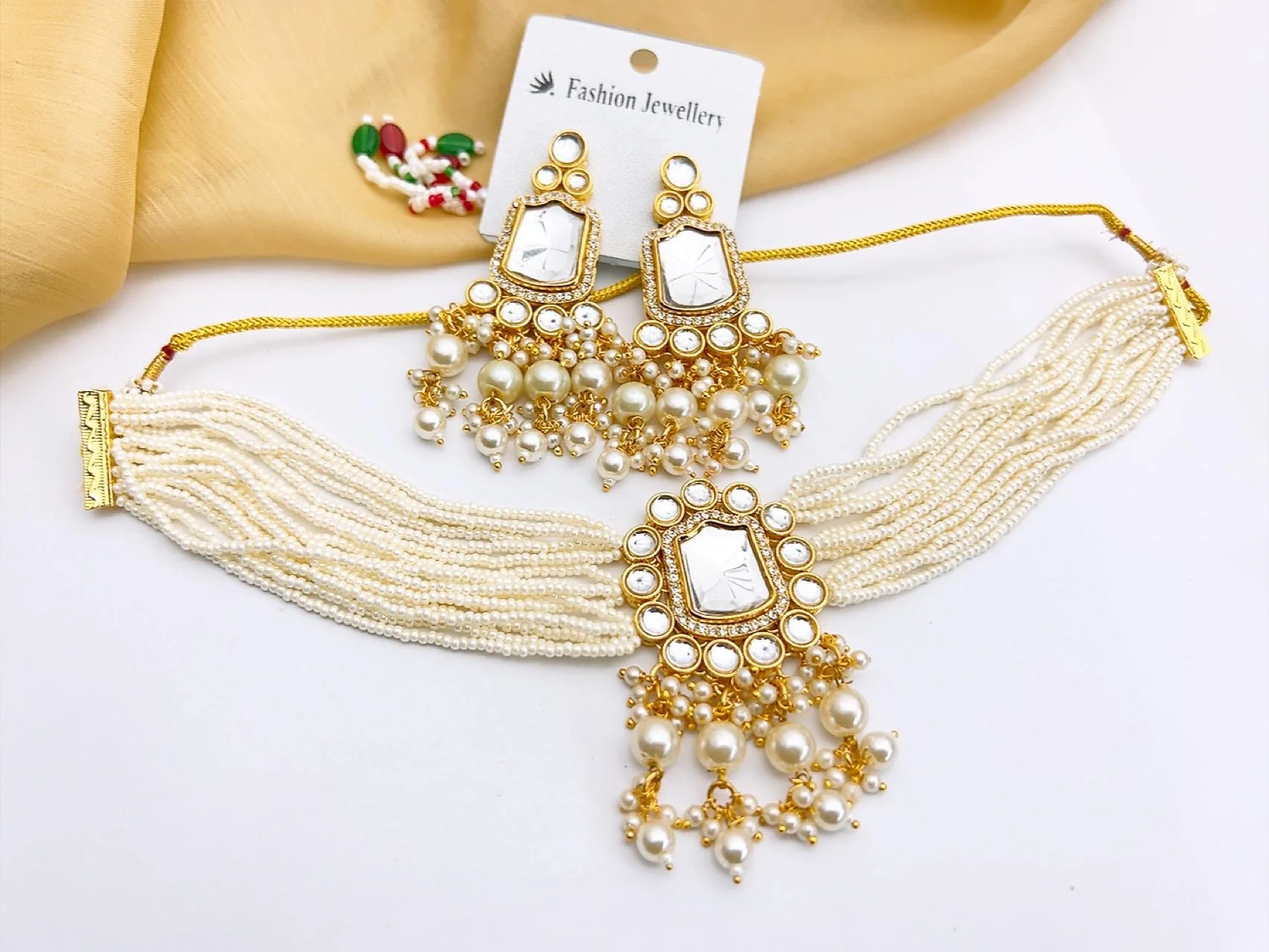 Premium White Kundan Choker Necklace Set with Drop Earrings Complete your wedding guest or bridesmaid attire with this graceful, adjustable imitation choker set. Accented with tiny pavé crystals, clear central mirror stones, and a cluster-pearl cascade, it delivers immediate luxury without the heavy weight or price tag.