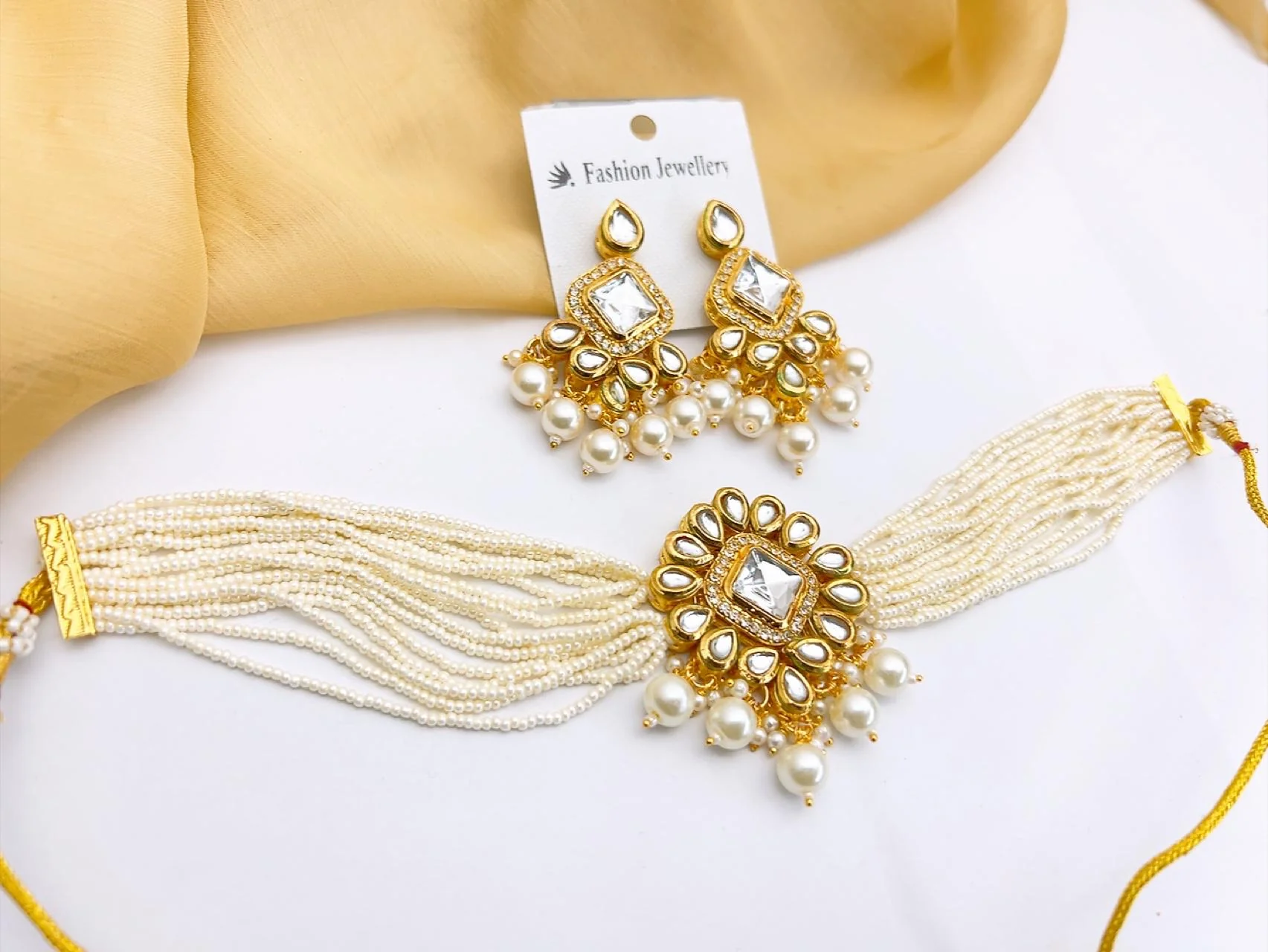 Premium White Kundan Choker Necklace Set with Drop Earrings A contemporary take on classic luxury costume jewellery. This lightweight, high-collar choker uses fine glass-mirror Kundan work and delicate seed bead strands to give you that highly coveted, clean aesthetic for the upcoming UK wedding season.