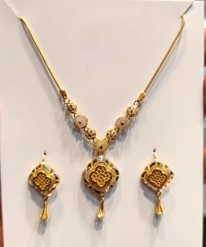 Shop a 22K gold quatrefoil medallion necklace and matching drop earrings with textured geometric detailing. Traditional-inspired jewelry for weddings and special occasions.