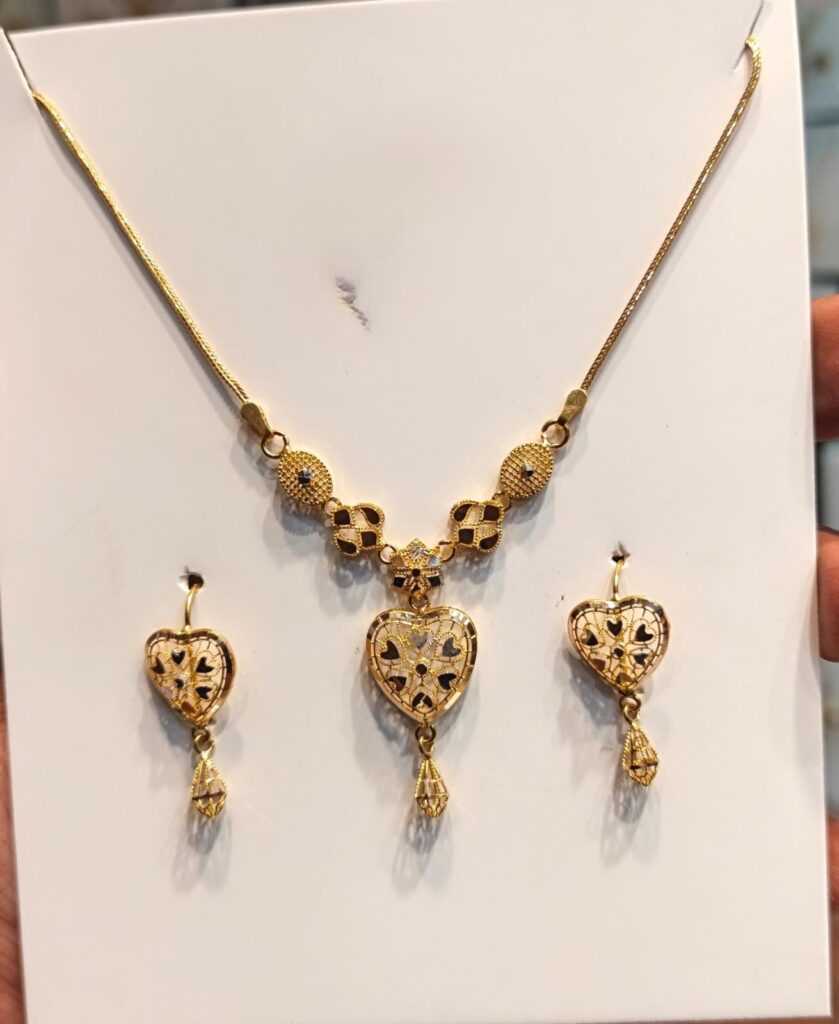 Shop the Modern Chicago Heart 22K Gold Jewelry Set featuring a heart-shaped yellow gold necklace and matching drop earrings with decorative contrasting details.