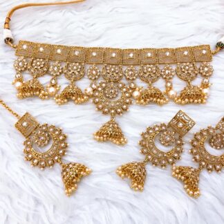 Shop our handcrafted antique gold-plated Kundan choker necklace set featuring miniature Jhumka drops, matching earrings, and Maang Tikka. Perfect for weddings & festive wear.