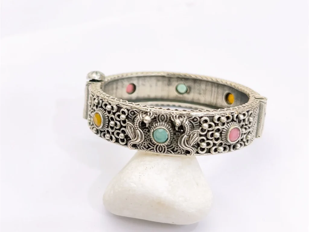 Shop a multicolor filigree cuff bracelet with pink, green and yellow decorative stones, ornate silver-tone detailing and a bold statement design.